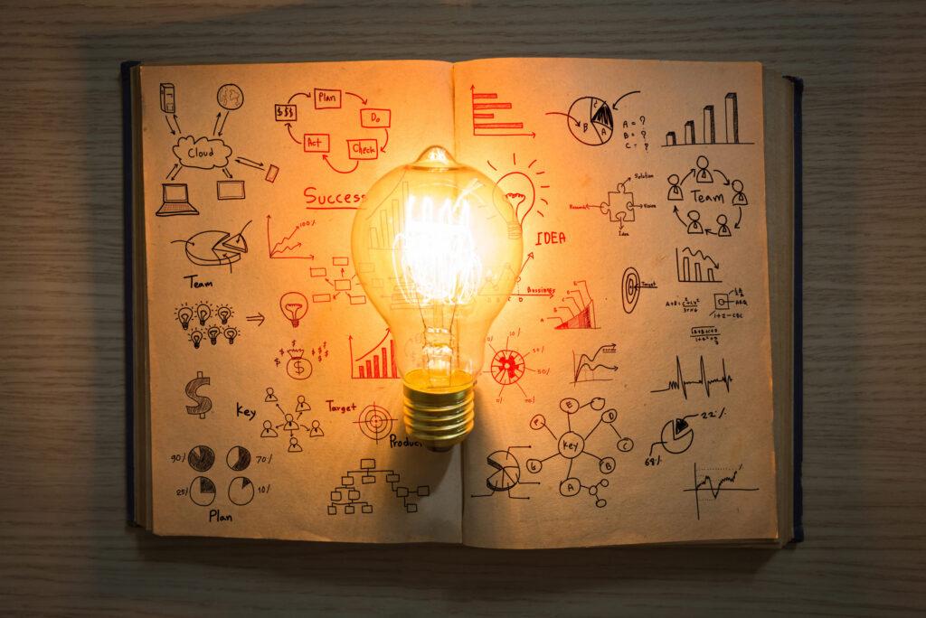 vintage book of business graph and light bulb on wood table